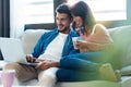 Happy beautiful couple using computer while sitting on the couch at home Royalty Free Stock Photo