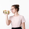 Happy beautiful cute teen girl in glasses and t-shirt with smile on face holding plate of cakes on white background Royalty Free Stock Photo