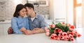 Happy beautiful cute young couple are sitting together on the kitchen with flowers. Love, celebration, romantic Royalty Free Stock Photo