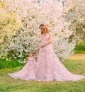 Happy beautiful family mom and daughter, spring blooming garden. Long luxury evening fantasy dresses powder pink color Royalty Free Stock Photo