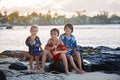 Happy beautiful fashion family, children, dressed in hawaiian shirts, playing together on the beach on sunset Royalty Free Stock Photo