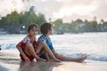 Happy beautiful fashion family, children, dressed in hawaiian shirts, playing together on the beach on sunset Royalty Free Stock Photo