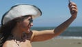 Happy beautiful female making selfie on smartphone at seaside, social networks