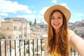Happy beautiful female tourist is taking a selfie smiling at the camera with the city of Matera on the background in Italy Royalty Free Stock Photo