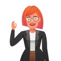 Happy beautiful girl in a business suit with red hair shows an OK gesture. Stylish young confident woman in glasses Royalty Free Stock Photo