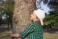 Happy beautiful girl hugging big tree in park . Loving nature .