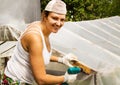 Happy beautiful girl with a screwdriver working in his garden, repairing a greenhouse