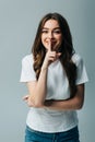 Beautiful girl in white t-shirt showing shh sign isolated on grey Royalty Free Stock Photo