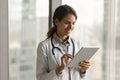 Happy beautiful Hispanic doctor woman using tablet Royalty Free Stock Photo