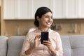 Happy beautiful Indian woman holding mobile phone, looking away Royalty Free Stock Photo