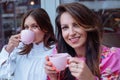 Happy beautiful ladies sitting together outdoors in cafe and enjoying drinking tea from pink cups closeup. Holiday party Royalty Free Stock Photo