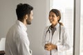 Happy beautiful Latin doctor woman speaking to young male colleague Royalty Free Stock Photo