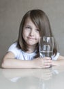 Happy beautiful little girl drinking clear water. Portrait of smiling baby holding transparent glass Royalty Free Stock Photo