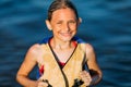 Happy beautiful little girl in a life jacket, swimming in the sea and showing a winning gesture. Summer holiday, vacation