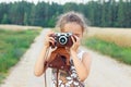 Happy beautiful  little girl in retro outfit  is taking pictures with old film camera Royalty Free Stock Photo