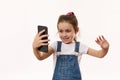 Happy excited little child girl, using smartphone, talks via video link, isolated over white background, copy ad space