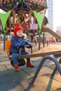 Happy beautiful little toddler girl having fun on swing in the playground. Baby smiles and laughing.