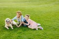 happy beautiful mother and daughter with golden retriever dog sitting on green lawn Royalty Free Stock Photo