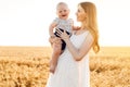 Happy beautiful mother with her baby on the golden wheat field Royalty Free Stock Photo