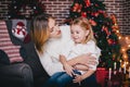 Happy beautiful mother and her little daughter posing near Christmas tree in a holiday interior Royalty Free Stock Photo