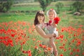 Happy beautiful mother lady posing with her cute little daughter in lovely scene of family summer life on meadow of daisy poppy fl Royalty Free Stock Photo