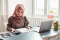 Happy beautiful muslim business woman brown hijab working about financial with business report and calculator in home office Royalty Free Stock Photo