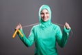 Happy beautiful muslim woman in green hijab or islamic sport wear standing, holding jump rope and looking at camera with toothy s Royalty Free Stock Photo