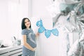 Happy beautiful pregnant caucasian woman with big belly in dress in the child room with balloons, future parrents Royalty Free Stock Photo