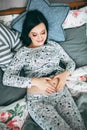 Happy beautiful pregnant caucasian woman with big belly in pajamas in the bedroom, future parrents, waiting for a child Royalty Free Stock Photo