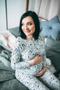 Happy beautiful pregnant caucasian woman with big belly in pajamas in the bedroom, future parrents, waiting for a child Royalty Free Stock Photo