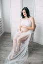 Happy beautiful pregnant caucasian woman with big belly in white underwear in the bedroom, future parrents, waiting for Royalty Free Stock Photo