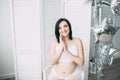 Happy beautiful pregnant caucasian woman with big belly in white underwear in the bedroom, future parrents, waiting for Royalty Free Stock Photo