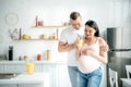 Beautiful pregnant couple holding orange juice in kitchen Royalty Free Stock Photo