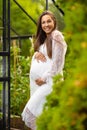 Smiling pregnant woman outdoor in her garden holding hands on belly Royalty Free Stock Photo