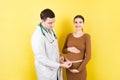 Happy beautiful pregnant young woman touching her bare tummy while a doctor is measuring it Royalty Free Stock Photo