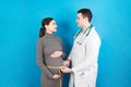 Happy beautiful pregnant young woman touching her bare tummy while a doctor is measuring it Royalty Free Stock Photo