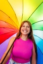 Happy beautiful pretty smiling young teen girl wearing bright pink top at colourful rainbow background