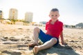 Happy beautiful smiling child sitting at the sand beach, look at camera