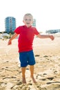 Happy beautiful smiling child jumping at the sand beach, looking at camera