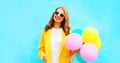 Happy beautiful smiling woman holds an air balloons in yellow coat Royalty Free Stock Photo