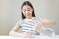 Happy beautiful, thirsty asian young woman, girl drinking, hand in holding, pouring water from jug into transparent glass from Royalty Free Stock Photo