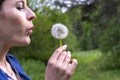 Happy beautiful woman blowing dandelion over sky background, having fun and playing outdoor, teen girl enjoying nature Royalty Free Stock Photo