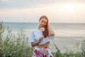 Happy beautiful woman blowing dandelion over sky and sea background, having fun and playing outdoor, Royalty Free Stock Photo