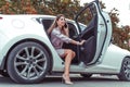 Happy beautiful woman calling phone, getting out car business sedan VIP class taxi, summer spring autumn city. Pink suit Royalty Free Stock Photo