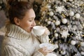 Happy beautiful woman enjoying drinking tea or coffee in living room with Christmas decor Royalty Free Stock Photo