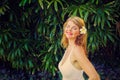 Happy woman in front of tropical green foliage. Vintage photo filter applied. Royalty Free Stock Photo