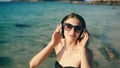 Happy beautiful woman listening to music on wireless headphones on beach near sea Royalty Free Stock Photo