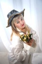 Happy beautiful woman with long blond hair and in black hat posing with flowers in studio on white background Royalty Free Stock Photo