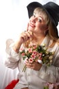 Happy beautiful woman with long blond hair and in black hat posing with flowers in studio on white background Royalty Free Stock Photo