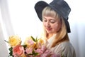 Happy beautiful woman with long blond hair and in black hat posing with flowers in studio on white background Royalty Free Stock Photo